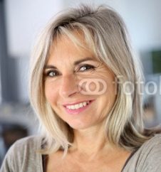 Senior_woman_standing_against_white_wall.jpg